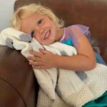 Our granddaughter with a cream blanket with gray sheep
